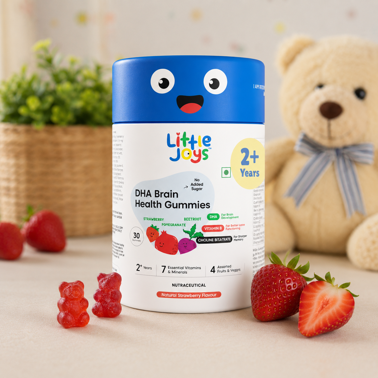 Container of Little Joys DHA Brain Health Gummies with strawberries and a teddy bear in the background