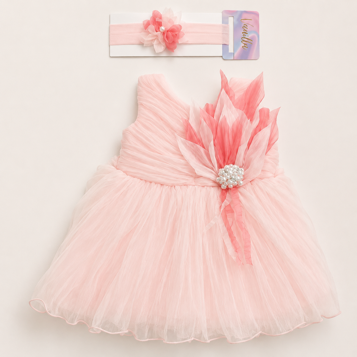 Peach pink girls’ party dress with matching floral headband, featuring a voluminous pleated skirt, layered floral embellishment with pearl detailing, and delicate ribbon accents on a light background.