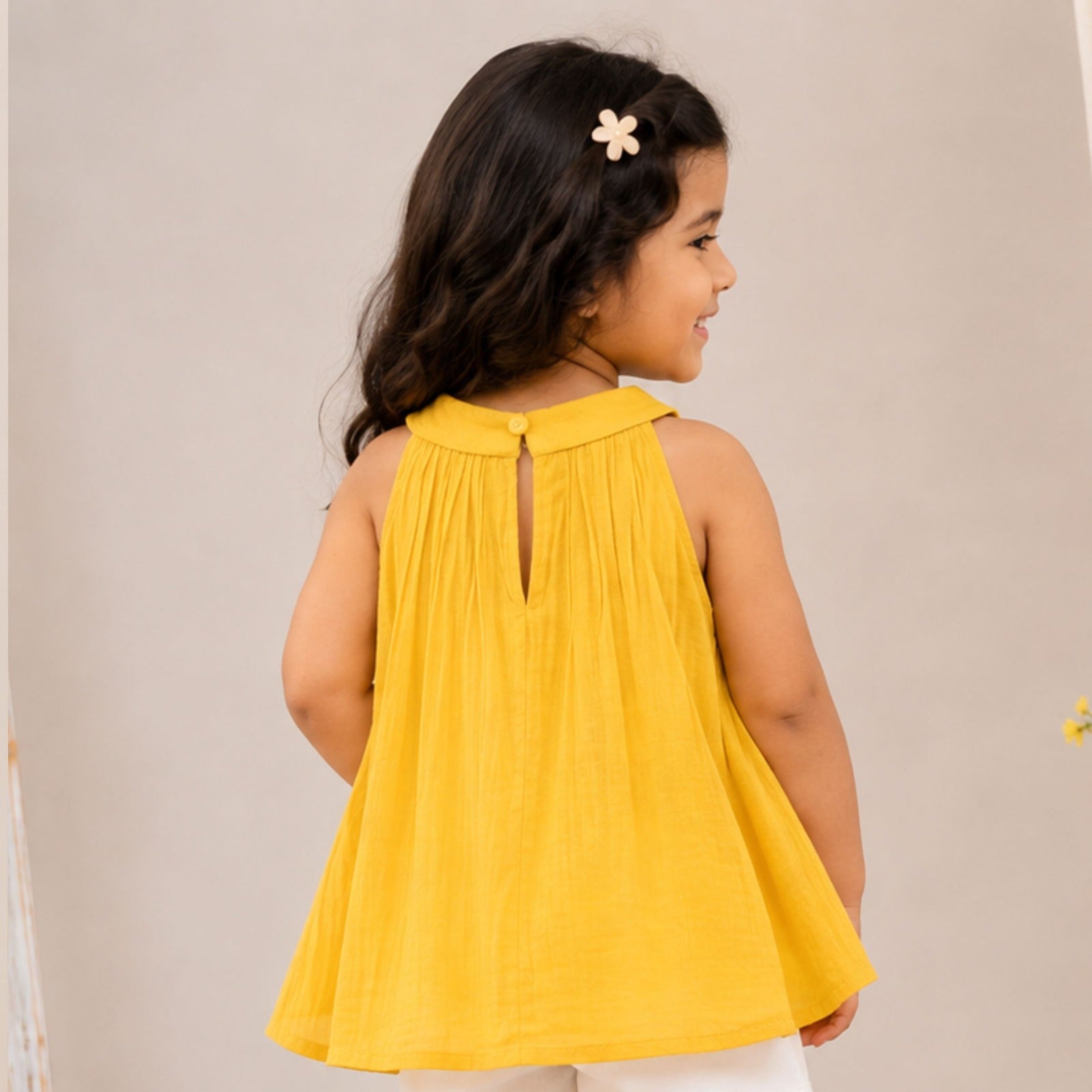 Back view of girl wearing Reverse X-Treme Yellow flared A-line sleeveless top with back button detail