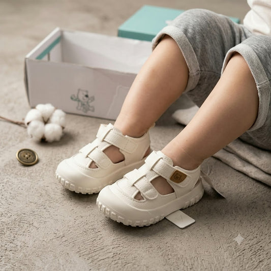Smile Baby boys white baby shoes with adjustable strap, worn by toddler