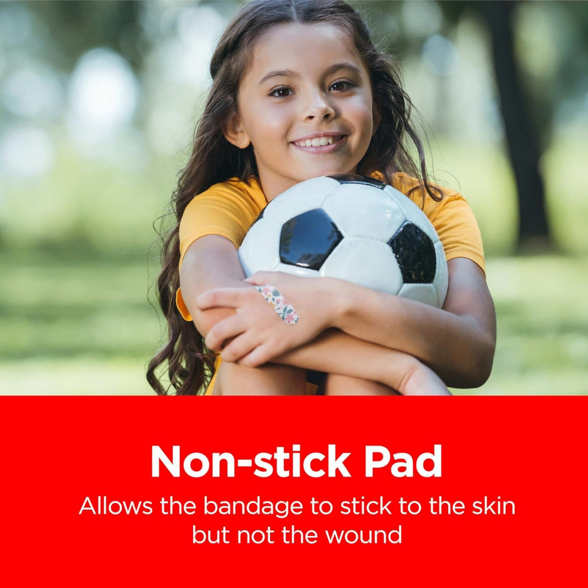 Child wearing patterned adhesive bandage while holding soccer ball